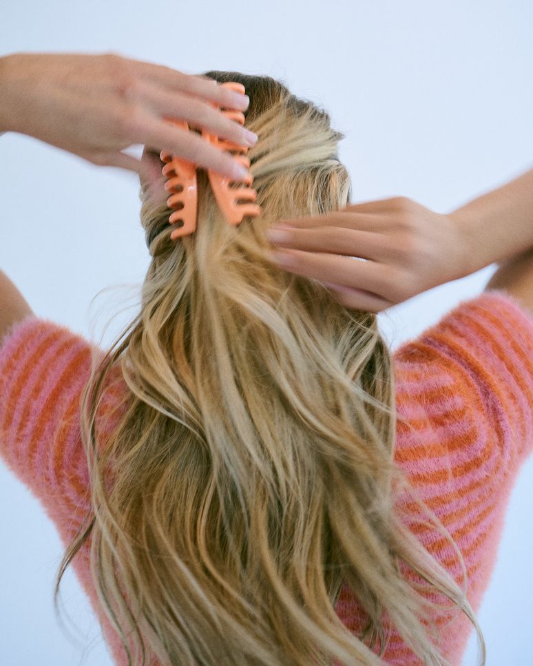 Woman clipping up a section of her blonde hair before installing tape-in extensions