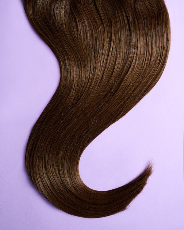 Close-up of light brown hair extensions with soft, caramel hues and a natural shine.
