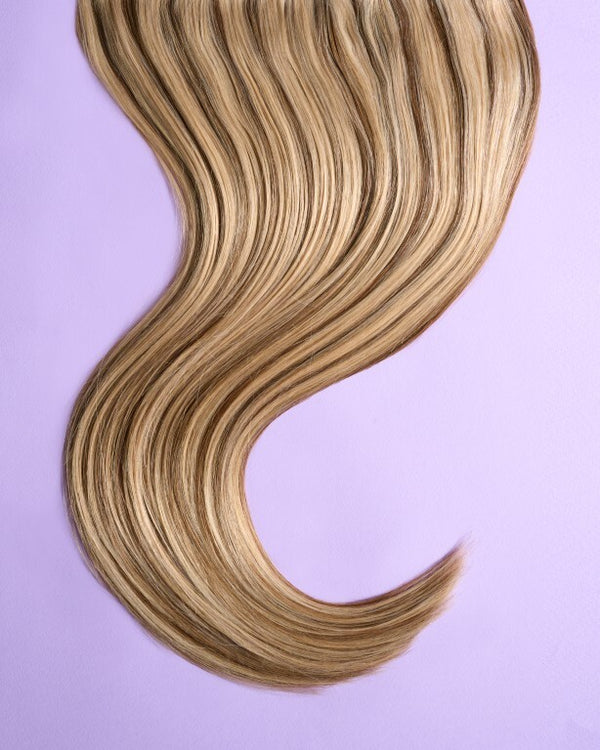 Detail view of blonde hair extensions with contrasting dark brown highlights, offering depth and dimension