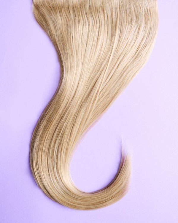 Detail view of strawberry blonde hair extensions with soft, warm red undertones and natural shine