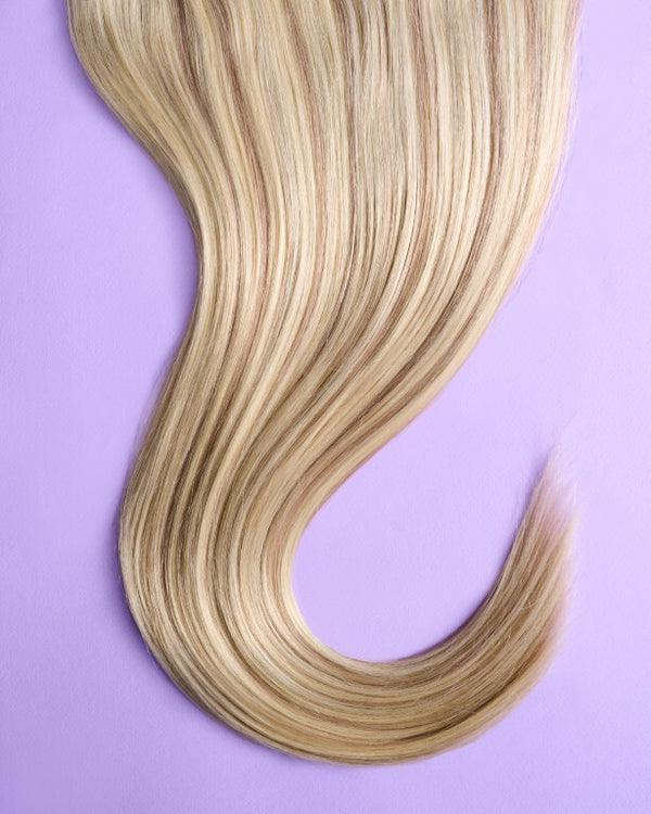 Close-up of blonde hair extensions featuring soft light brown highlights for added texture and warmth