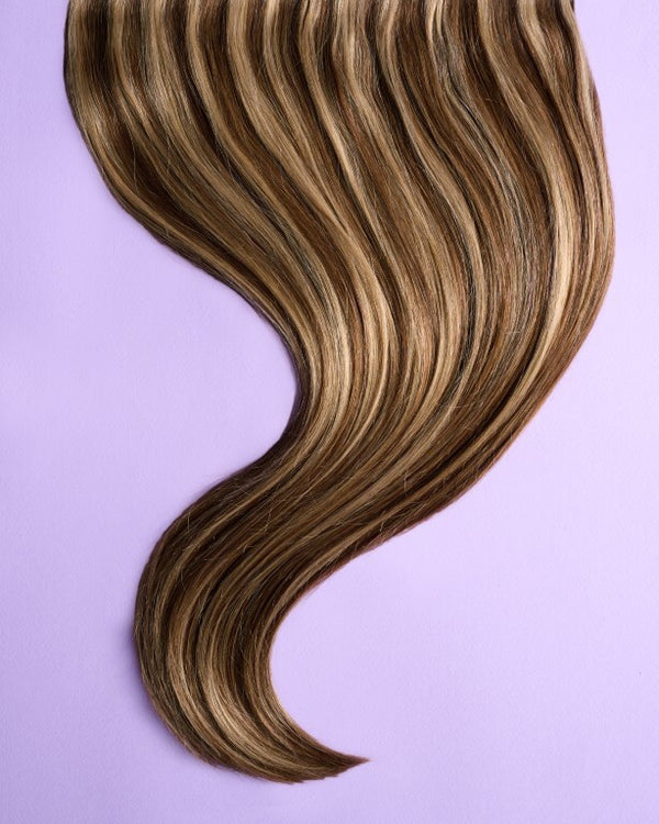 Detail view of dark blonde hair extensions with rich, warm blonde tones that blend effortlessly with natural hair