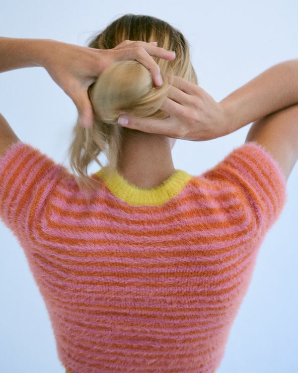 Woman with her hands at the back of her head, hair clipped up